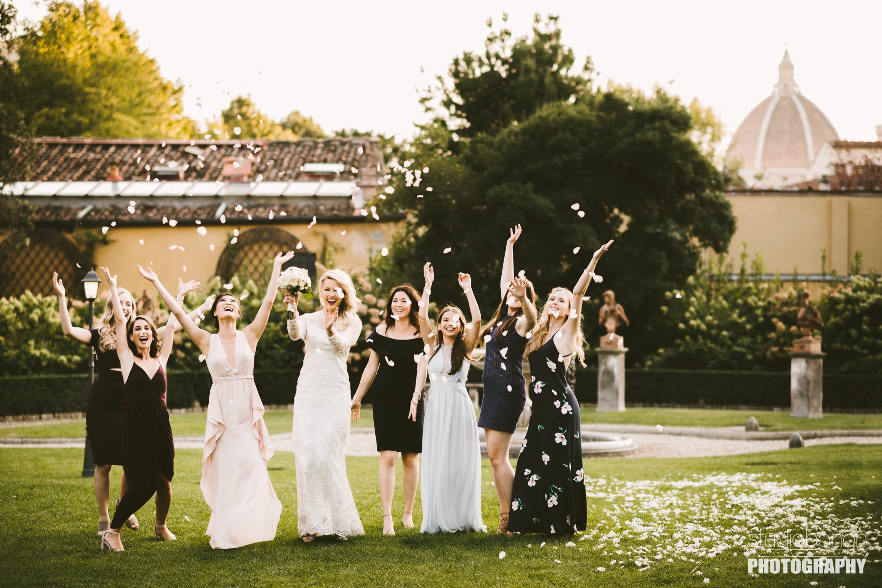 Excited bride with friends throw white petals at Hotel Four Seasons Florence. Destination Wedding in Florence