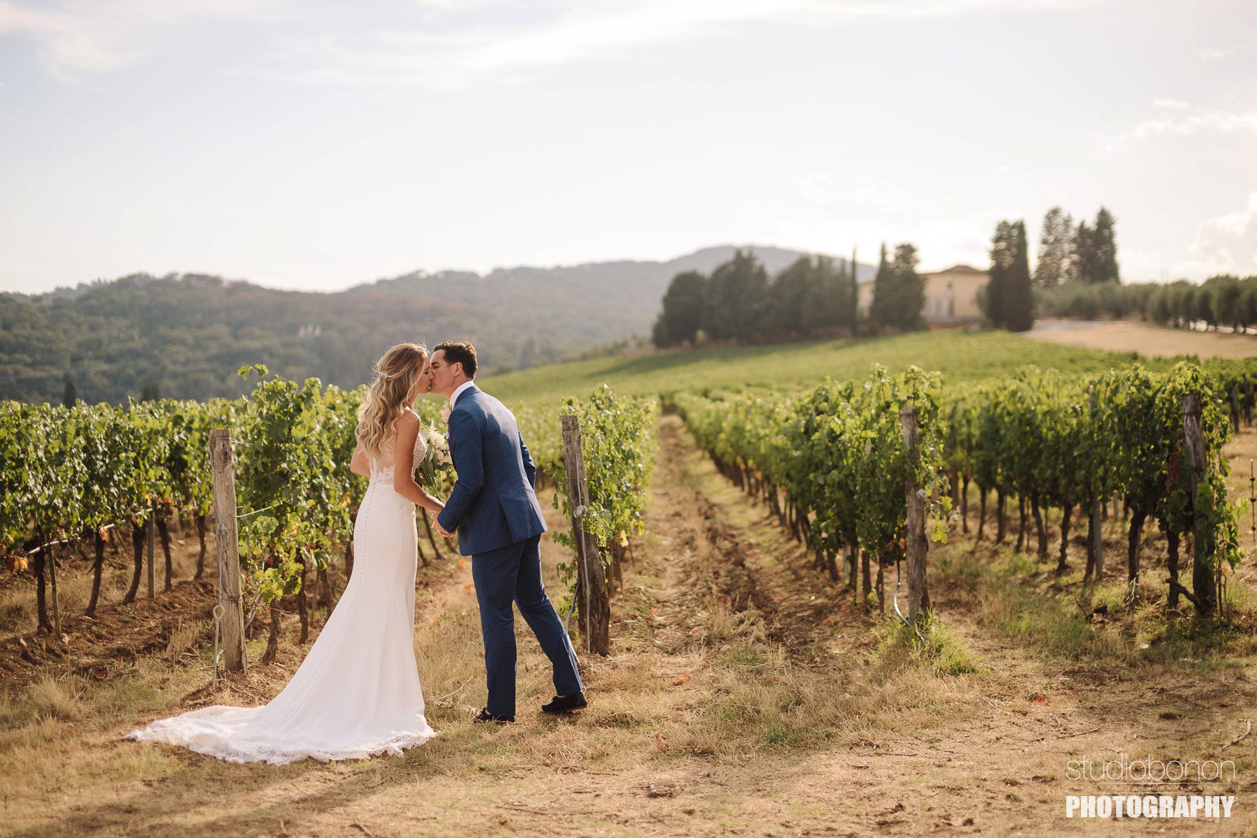 Bride and groom walk in a Tuscan vineyard into the countryside of Chianti